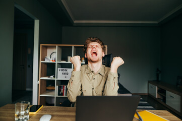 Angry young freelancer man working on laptop at home in quarantine and emotionally screaming...