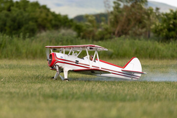 R/C biplane airplane taking off the grass with smoke behind