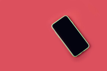 Mobile phone on a solid red background with place for text. View from the top.