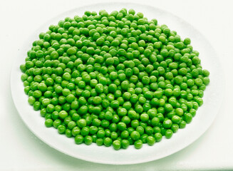 guisantes sobre plato con fondo blanco. peas on plate with white background.