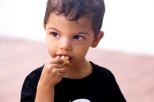 child eating a potato chip with an absent expression