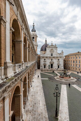 Naklejka na ściany i meble Italy, Loreto,square of Loreto with background the basilica with cloudy sky, portico to the side, perspective photo