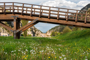 Italy, Macerata, Pioraco, 
wooden bridge,river with river among green meadows in the foreground, country background with cloudy sky