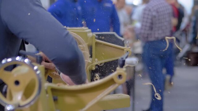 Carpentry, craftsmanship, design, manufacturing concept. Close up view - professional man carpenter using skew chisel for shaping piece of wood on wood turning lathe at workshop- super slow motion