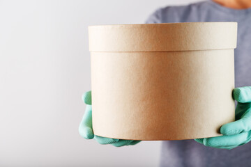 Parcel from a delivery service courier wearing rubber gloves and a mask.