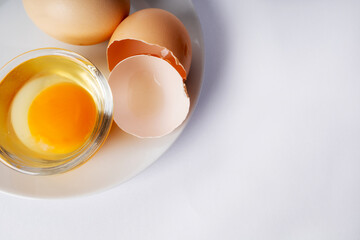 Image of yolk and squirrel in a transparent round cup on a plate. Egg in a transparent cup on a plate. Closeup