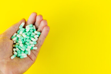 female hand holding blue tablets on a yellow probe with copyspace