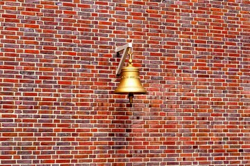 Glocke vor Ziegelmauer.