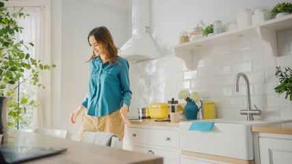 Attractive Young Female in Jeans Shirt and Brown Pants is Creatively Dancing in the Kitchen. Sunny...