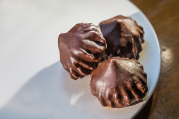 Three cone-shaped chocolates on a white plate close-up.