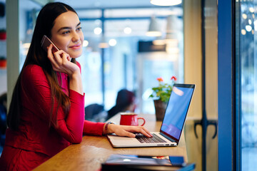 Skilled female copywriter talking on mobile discussing details of task updating application on...