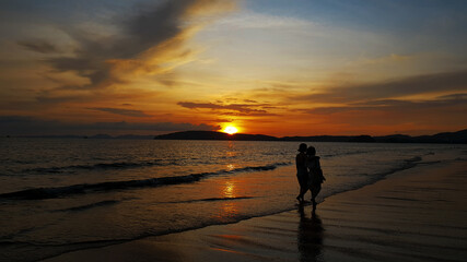 Fototapeta na wymiar couple walking on beach at sunset