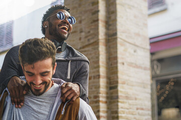 An African American descend guy having fun playing piggyback with his caucasian best friends....