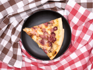 Two slice of pizza blanco. Comfortable home eating. Background of two dishcloth, red and brown colors on the wooden table. Top view
