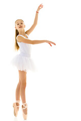 Naklejka premium Cute little girl in a tutu and pointe shoes dancing in the studio on a white background.