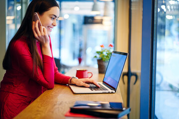 Skilled female copywriter talking on mobile discussing details of task updating application on...