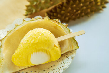 Durian ice cream stick on durian fruit shell on a white plate with durian fruit shell blurred background on white table, tropical and summer ice cream concept.