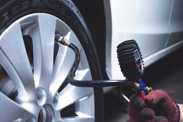 Car mechanic checks tire pressure in a tire store.