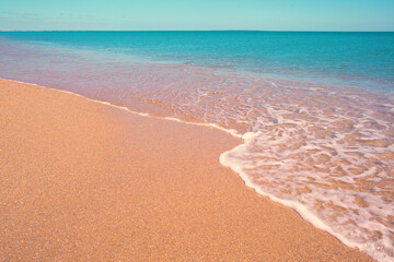 Plage et vague en bord de mer sous le soleil estival.