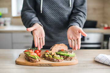 Close up of man making plate with avocado toast as fresh snack, day light. 