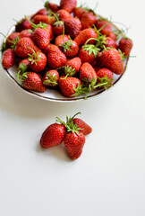 A lot of red, juicy strawberries on a plate. Red berries on a white background. Natural eco-product.