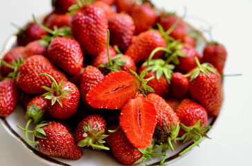 A lot of red, juicy strawberries on a plate. Red berries on a white background. Natural eco-product.