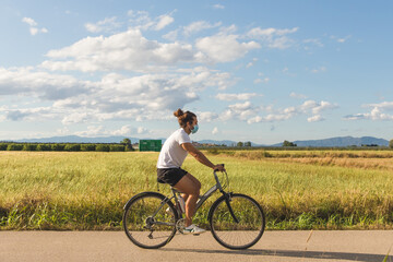 Young man on a bicycle on a country road wearing a mask