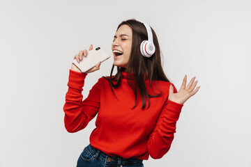 Photo of happy woman singing while using cellphone and headphones