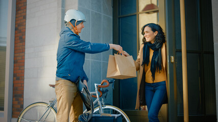 Happy Food Delivery Man Wearing Thermal Backpack on a Bike Delivers Restaurant Order to a Beautiful...
