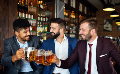 Handsome businessmen are drinking beer, talking and smiling while resting at the pub