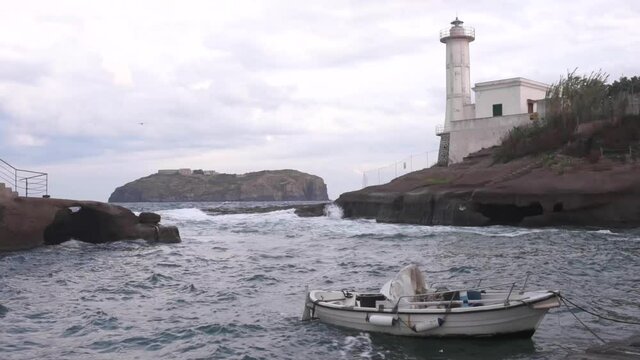 Bad weather, strong winds and high seas on Ventotene Island, Italy. Lighthouse and boat in the port. 