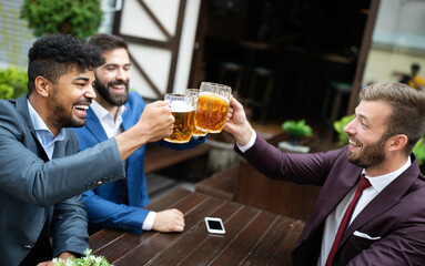 Meeting with the best friends. Happy young business men talking and drinking beer in a pub