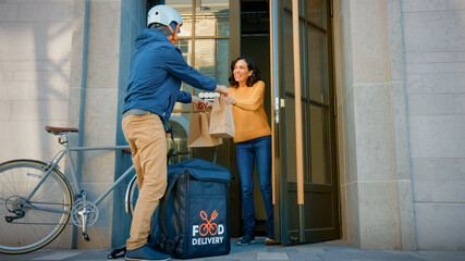 Happy Food Delivery Man Wearing Thermal Backpack on a Bike Delivers Restaurant Order to Beautiful Female Customer. Courier Delivers Takeaway Lunch to Gorgeous Girl in Urban Office Building.