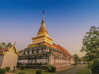 Naklejka premium view of golden pagoda (Chedi) with blue sky background, Wat Phra That Chang Kham Voravihara, Nan Province, northern of Thailand.