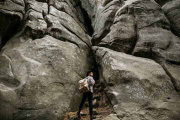 A hiker stands in front of a high cliff obstacle. Mountain tourism