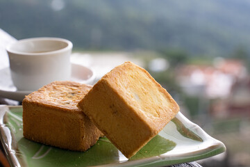 Delicious pineapple pastry in a plate for afternoon tea on wooden railing of a teahouse in Taiwan with beautiful landscape in background, close up.