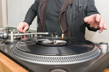 Hands of the DJ over the remote and the record while working