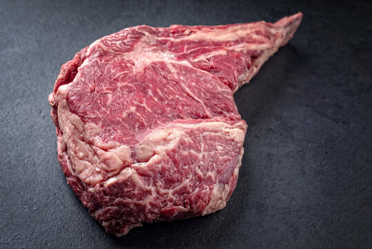 Raw dry aged Kobe tomahawk steak as close-up on a black board