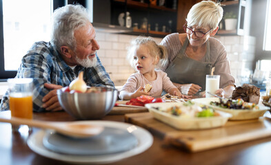 Happy grandparents with grandchildren making breakfast in kitchen