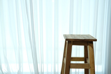 wooden stool chair beside see through window curtain