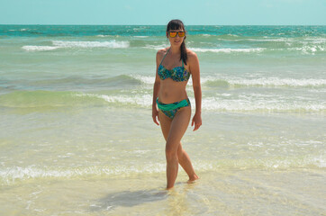 Young millennial girl in a swimsuit is having fun and enjoying life on vacation at the sea
