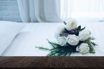 white bridal wedding rose flower bouquet on bed beside see through window curtain