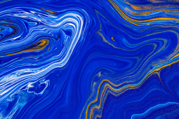 Fluid art texture. Background with abstract mixing paint effect. Liquid acrylic artwork with flows and splashes. Classic blue color of the year 2020. Blue, golden and white overflowing colors