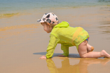 Obraz premium Happy caucasian child on a sandy beach in summer lifestyle. The concept of leisure activity, tourism and happy vacation