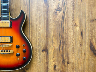 sunburst electric guitar made from a genuine alder wood Popular musician on veneer brown wood background with copy space on right for letter. business and music concept. Wallpaper or background.