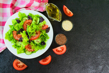 Light salad of fresh vegetables, herbs and flax seeds and sesame seeds on a black background. Copy space. Flat lay.