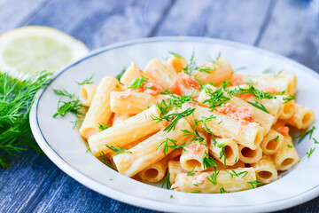  Italian home made  macaroni pasta with smoked salmon , creamy sauce and fresh dill on wooden background