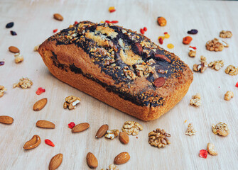 Traditional homemade marble pound cake with almond and walnuts, raisins and dry fruits around on the wooden table. Flat lay. Close up. Gluten free food concept.