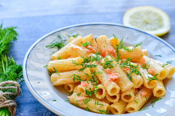  Italian home made  macaroni pasta with smoked salmon , creamy sauce and fresh dill on wooden...