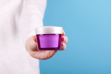 Cream in jar in hand.